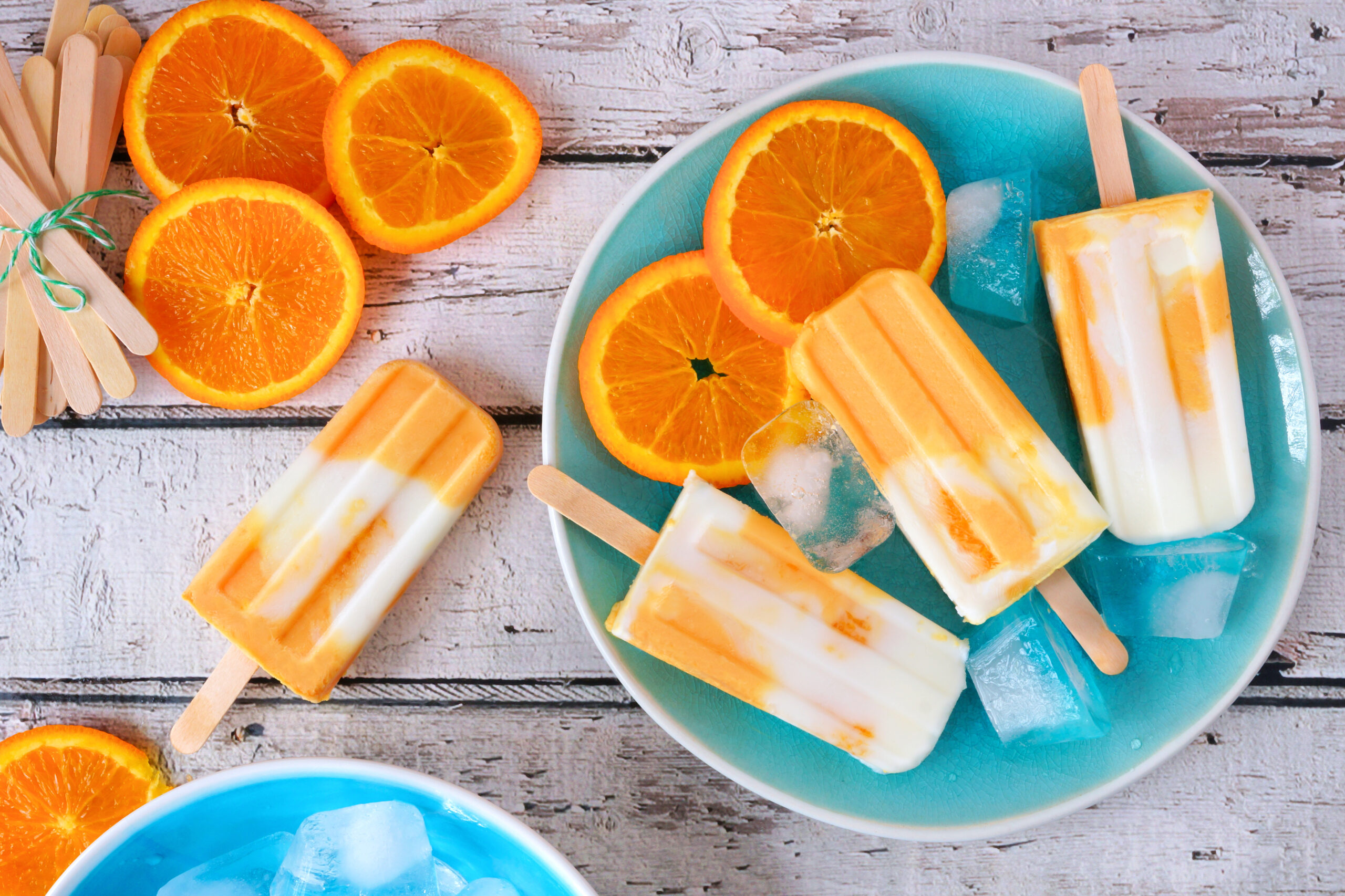 Orange yogurt popsicles on a blue plate, top view table scene ag